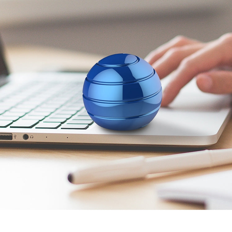Blue rotating tabletop ball gyroscope toy on a laptop keyboard with user hand nearby.