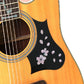 Cherry blossom decals on black pickguard section of acoustic guitar with white flowers