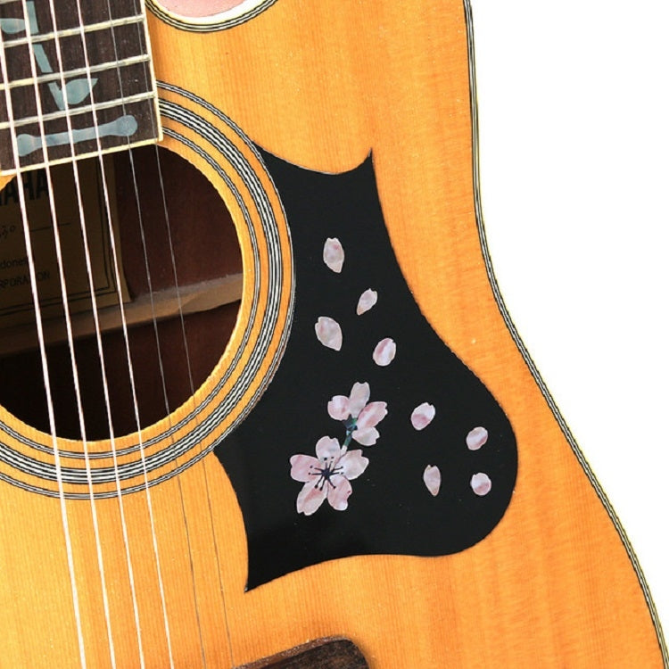 Cherry blossom decals on black pickguard section of acoustic guitar with white flowers