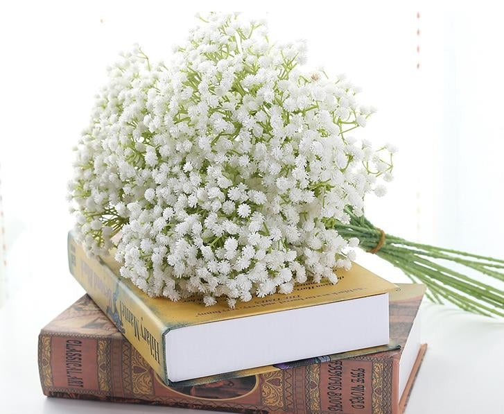 Artificial baby's breath bouquet with dense white mini flowers on books