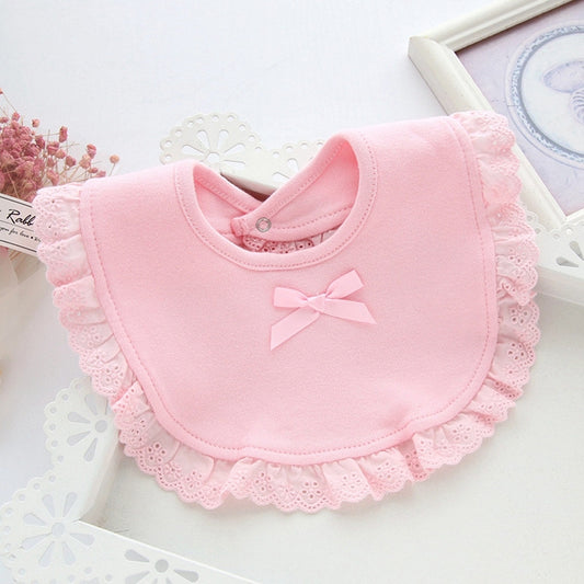 Pink baby bib with round neck, scalloped lace trim, and small bow applique at center.