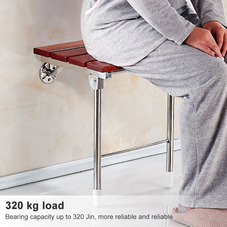 Wall-mounted folding shower chair with wood slatted seat and chrome legs used by person
