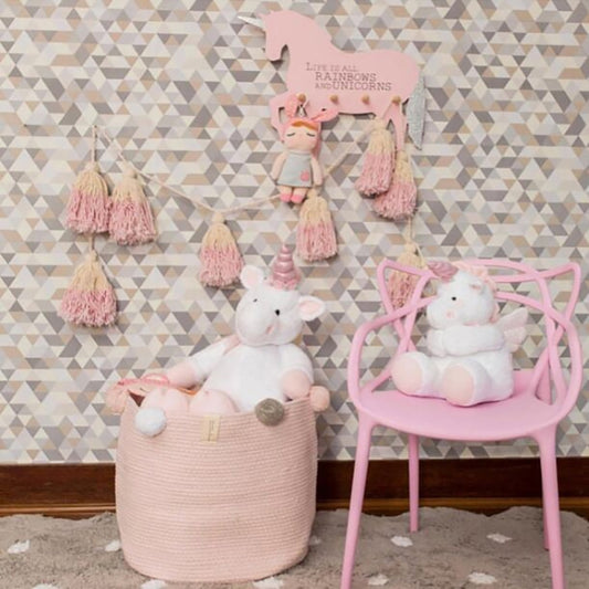 Beige fabric storage basket with pom-pom trim, holding plush toys