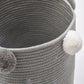 Light gray fabric storage basket with textured weave and pom-pom side accent