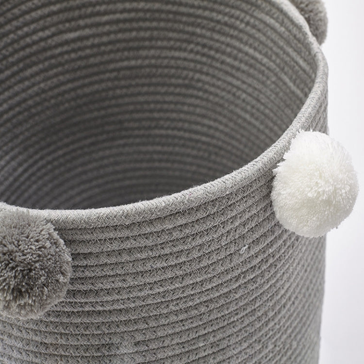 Light gray fabric storage basket with textured weave and pom-pom side accent