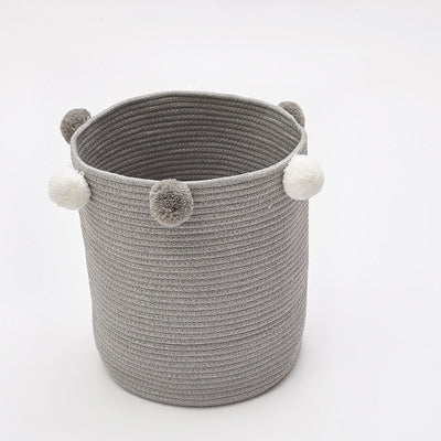 Gray round fabric storage basket with pom-pom accents around the top rim
