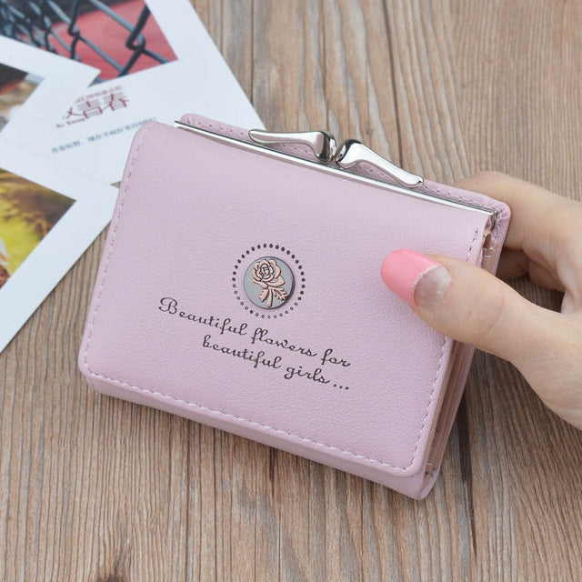 Pink mini folding wallet coin purse with floral emblem and kiss-lock clasp, stitched edges