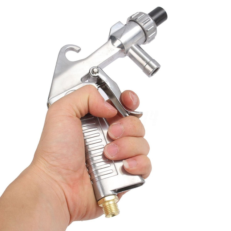 Handheld pneumatic sandblasting gun held in hand, metal body with brass connector