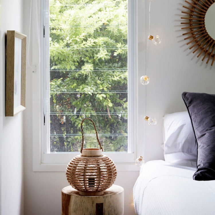 Copper wire LED string lights with warm clear globe bulbs, hanging near window and bed