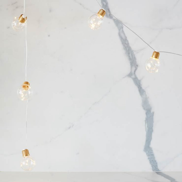 Copper wire LED string lights with warm clear mini globe bulbs on cord, close-up