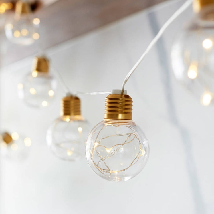Copper wire LED string lights with clear G45 globe bulb and gold base, foreground close-up
