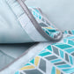 Close-up of waterproof changing pad fabric with teal geometric print and gray binding seam.