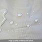 Waterproof changing pad fabric surface with visible water droplets on light gray material.