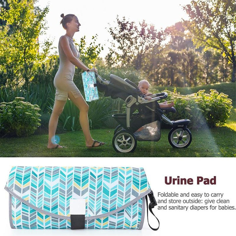 Folded waterproof changing pad with teal leaf pattern, gray edging, and black carry handle.