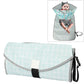 Foldable waterproof changing pad with light teal geometric pattern, gray sides, and black strap.