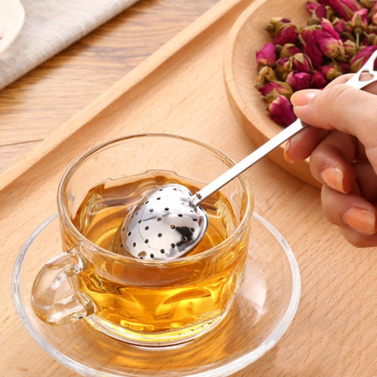 Heart-shaped stainless steel tea infuser spoon over a cup of tea