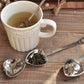 Set of two heart-shaped stainless steel tea infuser spoons on a wooden surface