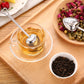 Heart-shaped stainless tea infuser spoon resting in a cup of clear tea