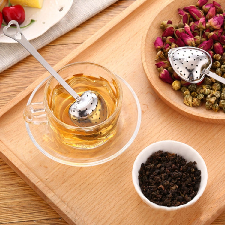 Heart-shaped stainless tea infuser spoon resting in a cup of clear tea