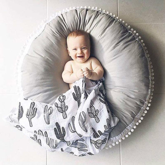 Gray round baby bean bag chair with pom-pom trim, supported center cushion