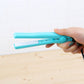 Mini hair straightener in blue, held in hand with power cord connected