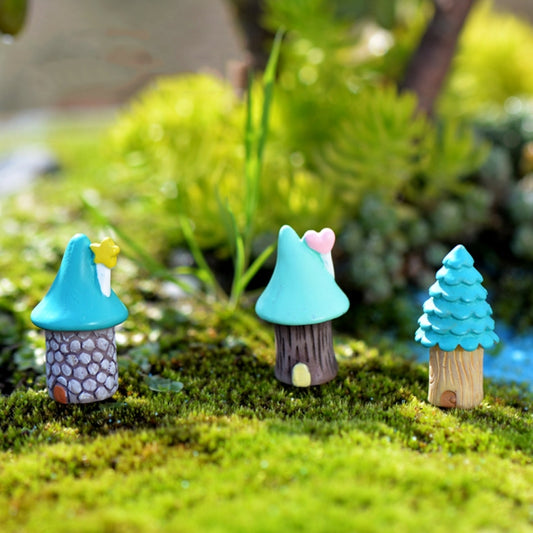 Mini teal-roof tree house ornaments on moss: pink heart, yellow star, and blue evergreen