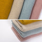 Folded thick knit scarves in pink, beige, and blue-gray with textured knit surface