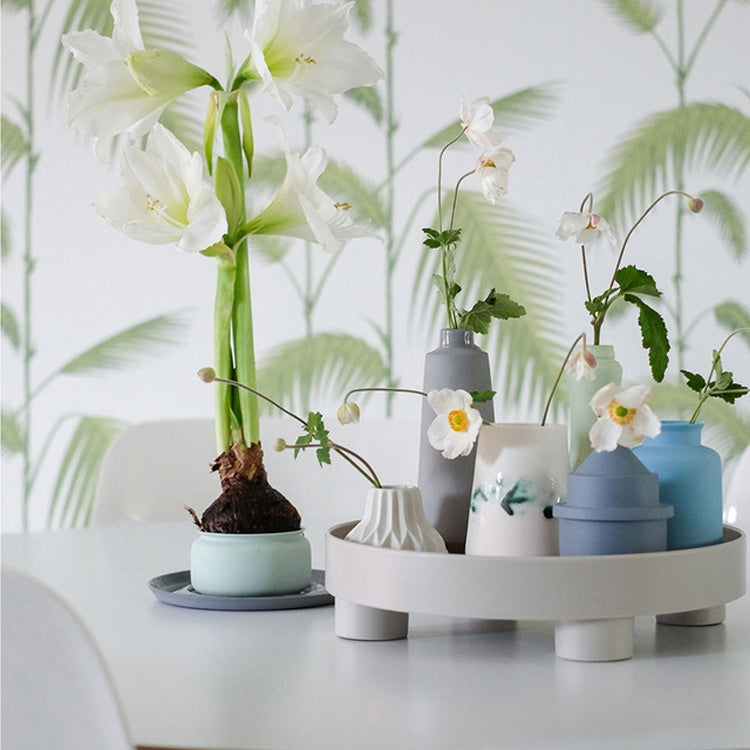 Round desktop storage tray with scalloped rim and three feet, holding small decor vases
