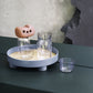 Round tray with beige center and dark feet, holding clear drinking glasses and sponge