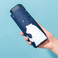 Mini pocket folding umbrella held in hand, navy blue with white bear print cover
