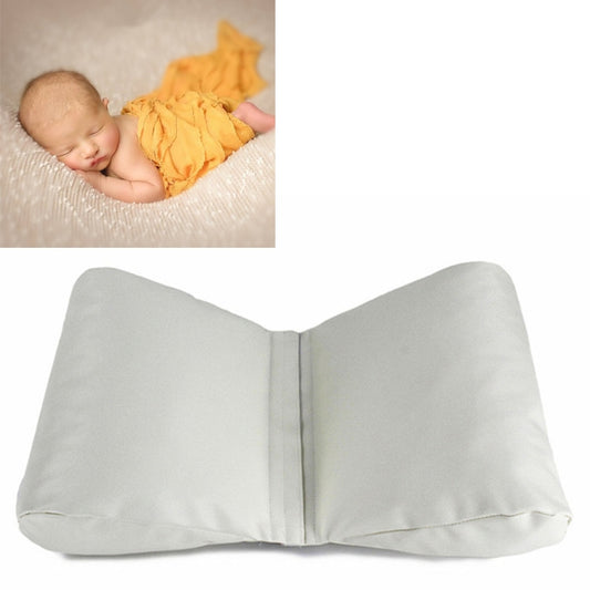 Newborn positioning cushion prop with baby lying on a textured white padded support