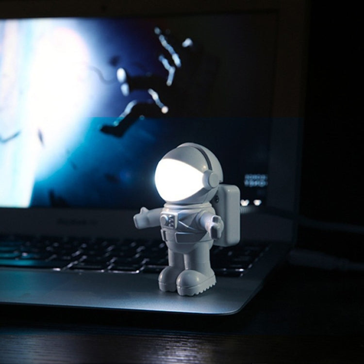White astronaut USB LED desk night light, glowing helmet on a laptop
