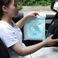 Aqua car garbage bag held open in the car, showing cartoon face label