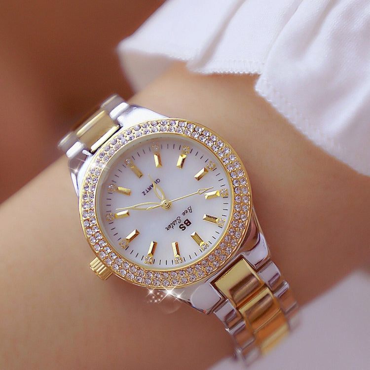 Women’s round watch on wrist with white dial, rhinestone bezel, and metal link bracelet