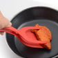 Red silicone omelette spatula lifting food in a nonstick frying pan