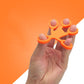 Orange silicone humanoid finger exercise pull ring with five finger loops.