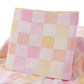 Pink checkered cotton towel with scalloped top edge and visible fabric texture