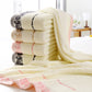 Stack of cream cotton bath towels with coordinated patterned borders and soft plush pile.
