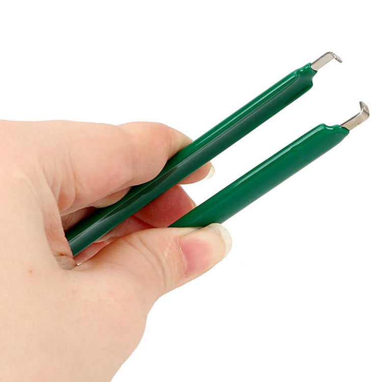 Green IC desoldering tweezers held in hand with dual pointed metal tips