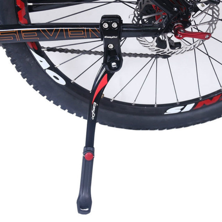 Bicycle parking rack kickstand with black legs and red release button near wheel