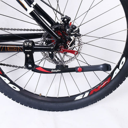 Bicycle kickstand mounted to frame with black arms and red release button