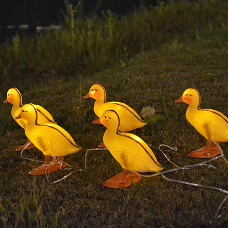 Yellow duck solar stake lights with glowing heads, orange feet, and clear connection wire