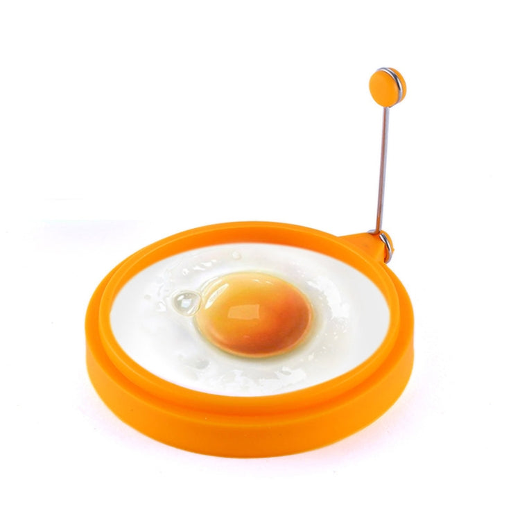 Orange round silicone egg ring mold with metal handle, holding a fried egg center.
