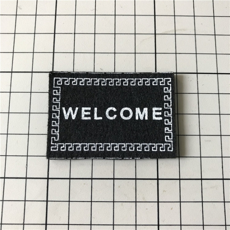 Black mini welcome mat with 'WELCOME' text and Greek-key border