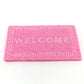 Pink dollhouse welcome floor mat with 'WELCOME' text and Greek-key border