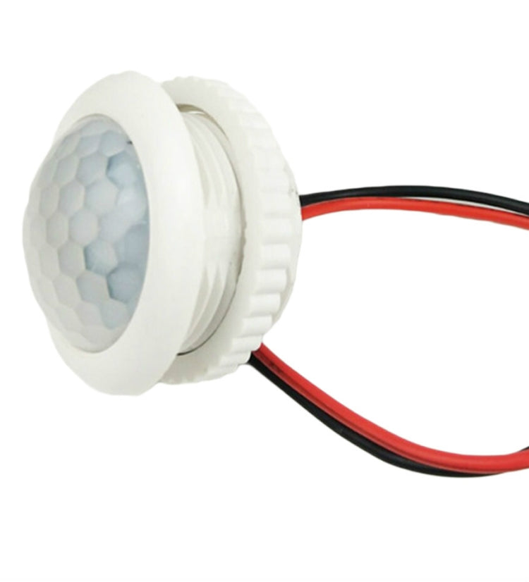 Back view of round white PIR sensor with wiring terminals and red/black leads