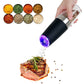 Black electric salt and pepper grinder with purple LED glow dispensing spices