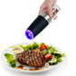 Black electric pepper grinder with purple LED dispensing spices onto a plated meal