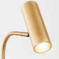 Gold cylindrical spotlight head on a curved stand, lit bulb at the opening.