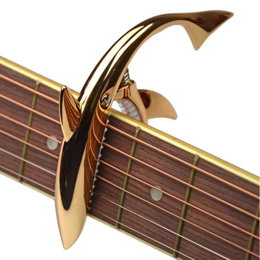 Rose gold shark-shaped guitar capo with spring clamp mechanism for strings